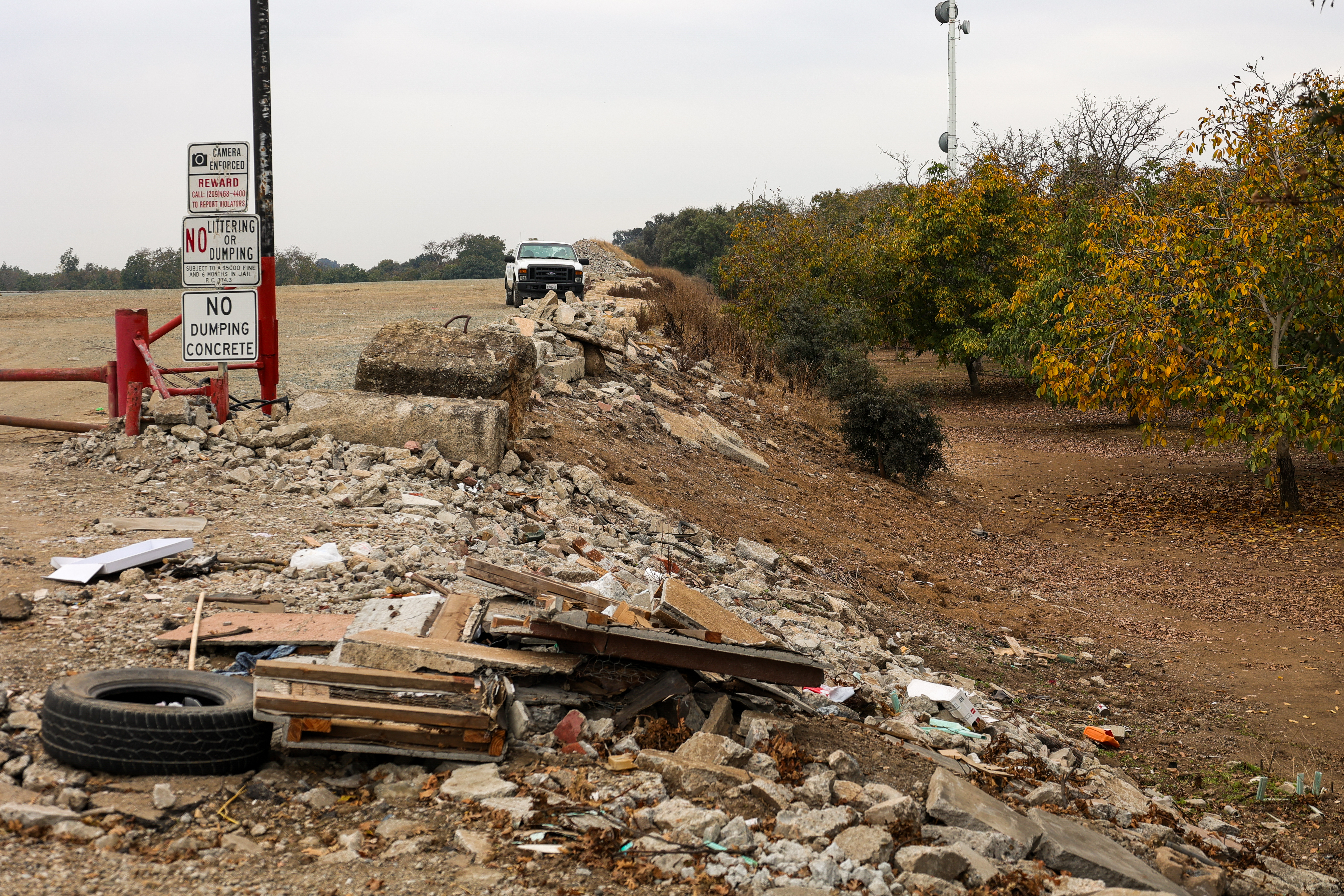Illegally dumped refuse on a levee in front of a No Illegal Dumping Sign